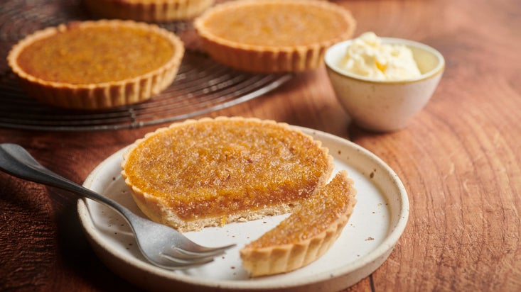 A short crust pastry based tart with a fork sat on a plate.